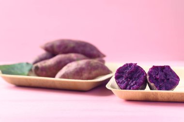 Pembe arka planlı, doğal tabakta, yemeye hazır mor patatesler.