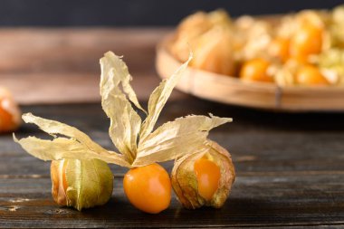 Tahta arka planda, sağlıklı tropikal meyveler üzerinde Cape bektaşi üzümü (Physalis peruviana)