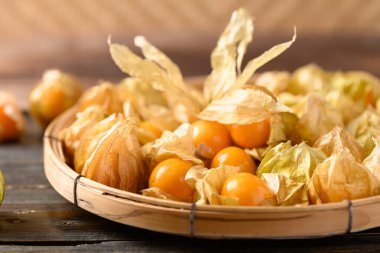 Tahta, sağlıklı tropikal meyveler üzerinde bambu sepetinde altın çilek (Physalis peruviana)