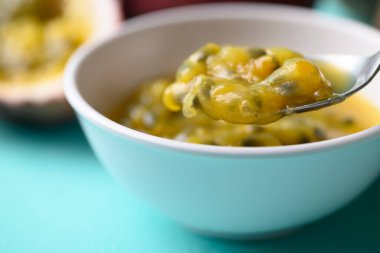 Pastel renkli arka planda yemek için kaşık ile tutkulu meyve suyu yaz mevsiminde tropikal meyve.