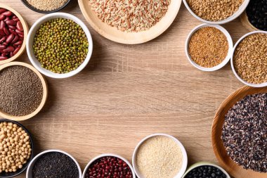 Çeşitli tahıl, tahıl, fasulye, baklagil ve tohum ahşap arka planda, gıda malzemeleri, masa üstü görünümü