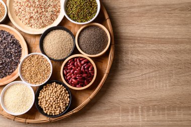 Çeşitli tahıl, tahıl, fasulye, baklagil ve tohum ahşap arka planda, gıda malzemeleri, masa üstü görünümü