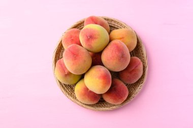 Pembe arka planda sepetteki şeftali meyvesi, Üst Manzara