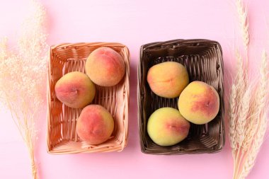 Pembe arka planda sepetteki şeftali meyvesi, Üst Manzara