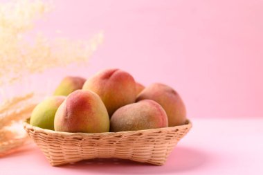 Pembe arka planda şeftali meyvesi sepeti