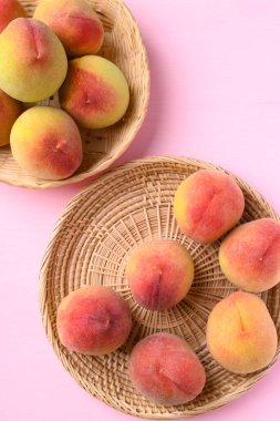 Pembe arka planda sepetteki şeftali meyvesi, Üst Manzara