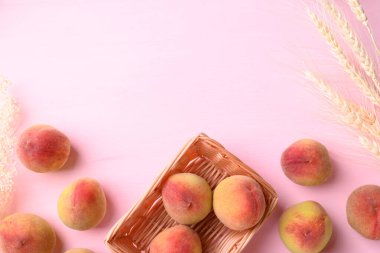 Pembe arka planda, şeftali meyvesi sepeti içinde kopyalama alanı