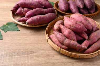 Tahta arka planda sepetin içinde çeşitli tatlı patatesler