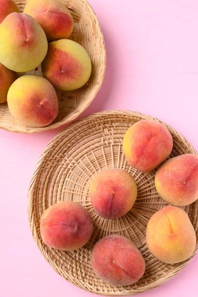 Pembe arka planda sepetteki şeftali meyvesi, Üst Manzara