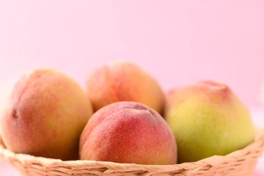 Pembe arka planda Asya şeftali meyvesi sepeti