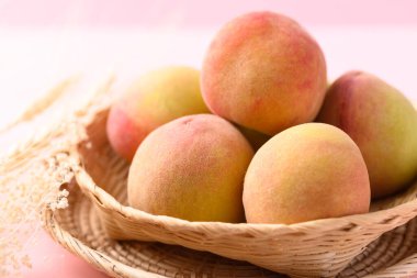 Asian peach fruit in basket on pink background