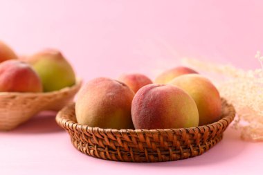 Pembe arka planda Asya şeftali meyvesi sepeti