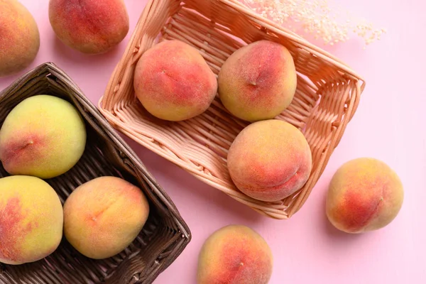 Pembe arka planda Asya şeftali meyvesi sepeti