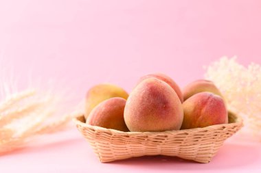 Pembe arka planda Asya şeftali meyvesi sepeti