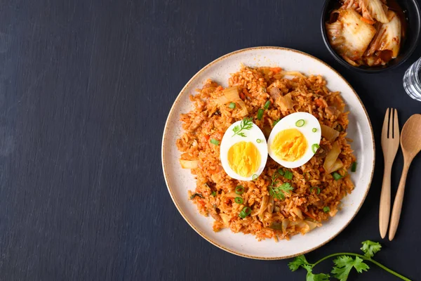 Siyah arkaplanda haşlanmış yumurtalı Kore kimchi pilavı.