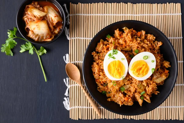 Siyah arkaplanda haşlanmış yumurtalı Kore kimchi pilavı.