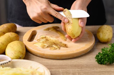 Elinizde bıçak ve yemek pişirmek için patates soyuyorsunuz.