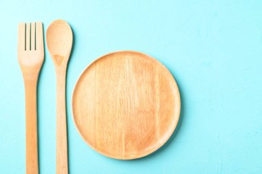 Mutfak gereçleri (ahşap tabak, çatal ve kaşık) renk arka planında