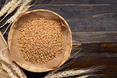 Tahta zemin üzerinde tam buğday taneleri, yemek malzemeleri, masa üstü manzarası.