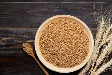 Tahta zemin üzerinde doğal tabakta kepekli buğday, yemek malzemeleri, masa üstü manzarası.