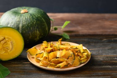 Pumpkin chips on plate with wooden background, Healthy vegan snack