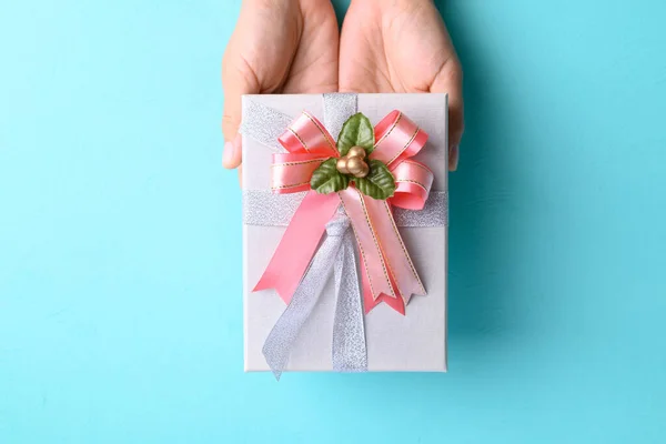 Silver gift box with pink ribbon in hand on light blue color background, Present for giving in special day and holiday