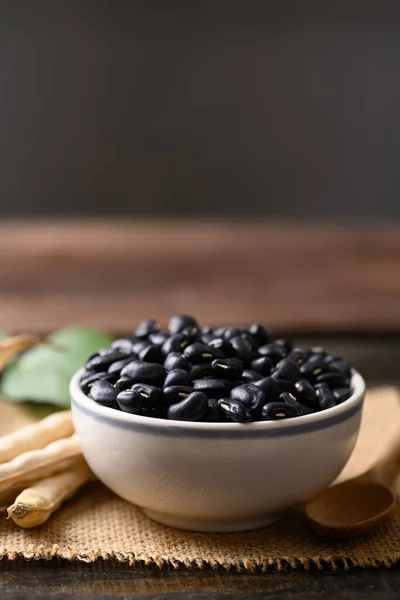 Black kidney bean seed in bowl on wooden background