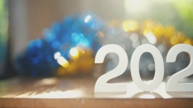 Beyaz numara 2022 yeni yıl metni ahşap masa üzerinde renkli bulanık arkaplan ve sabah doğal ışık, kamera kaydırma görüntüleri