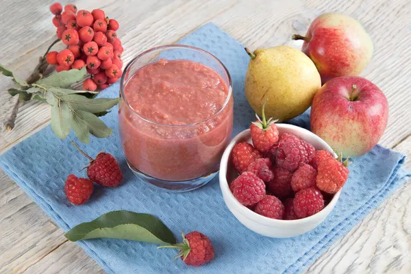 Detailní záběr sklenice smoothies ze sezónního ovoce - jablka, hrušky a maliny na modrém ubrousku. — Stock fotografie