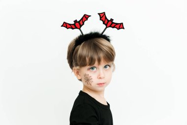 Siyah elbiseli ve yarasa çemberli şirin bir kız. Cadılar Bayramı kutlaması. Beyaz arka plan. Minimalist stil