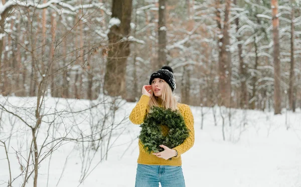冬を屋外で楽しむ美しい若い女の子 森や公園で雪と遊ぶかなりの女性 ブロンド女の子とともに緑のクリスマス花輪 — ストック写真