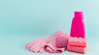Mavi arka plandaki pembe malzeme koleksiyonunu temizliyorum. Ev işi konsepti. Temizlik malzemesi, bez, lastik eldiven, peçete ve fırça pedi.