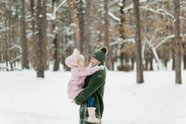 幸せと笑顔の若い母親と彼女の小さな娘一緒に冬の森の外で時間を過ごす — ストック写真