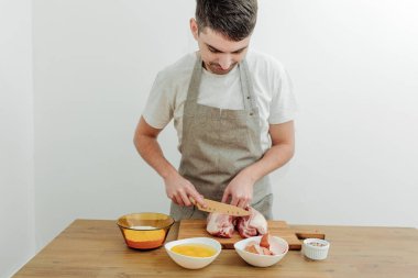 Yemek pişirme devam ediyor. Et, yumurta, un, masaya tuz, kesim tahtası ve bıçak..