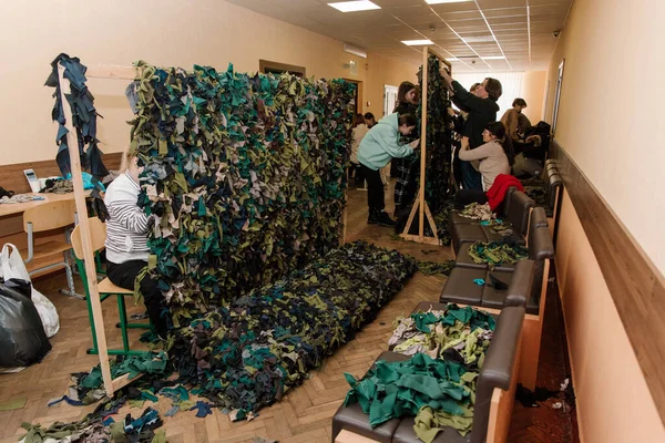 KYIV, UKRAINE - Mart. 11, 2022: Ukrayna 'ya karşı Rusya Savaşı. İnsanlar ordu için kamuflaj ağları örmeye gönüllü oluyor. Gönüllü olmak, askeri konsepte yardım etmek..