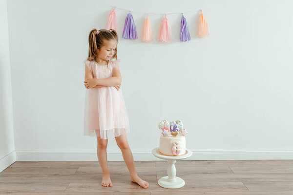 Cute little girl in pink dress with bithday cake. Six years old celebration. Birthday decoration