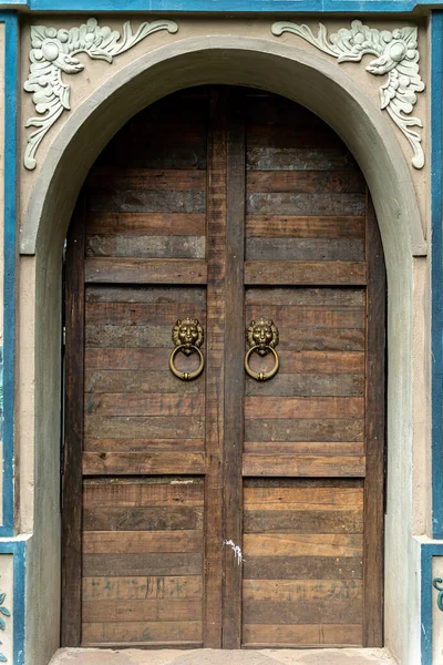 Old door wood stone texture. Vietnamese style. Arch of stone with closed wooden door. Entrance to local house in Vietnam. Travel and background concept.