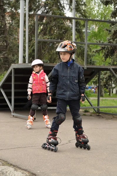 Flickan och pojken rullas på rullarna — Stockfoto