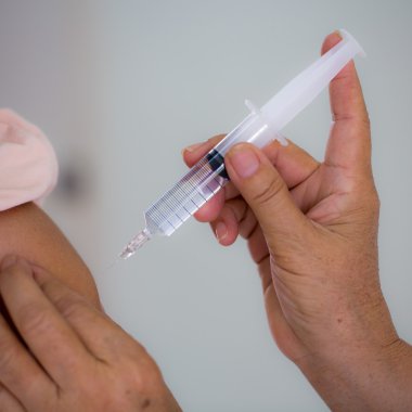 Doktor elinde şırınga tutuyor.