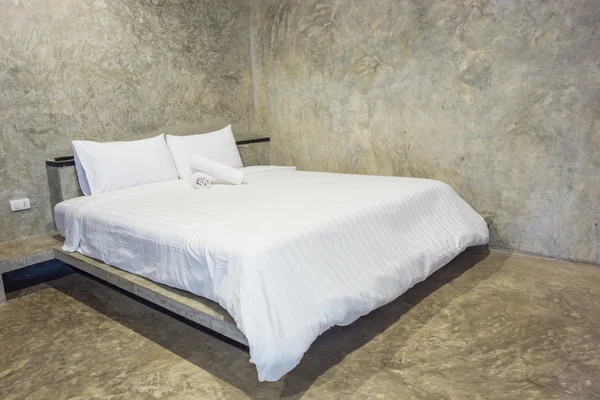 White bed with gray cement wall — Stock Photo, Image