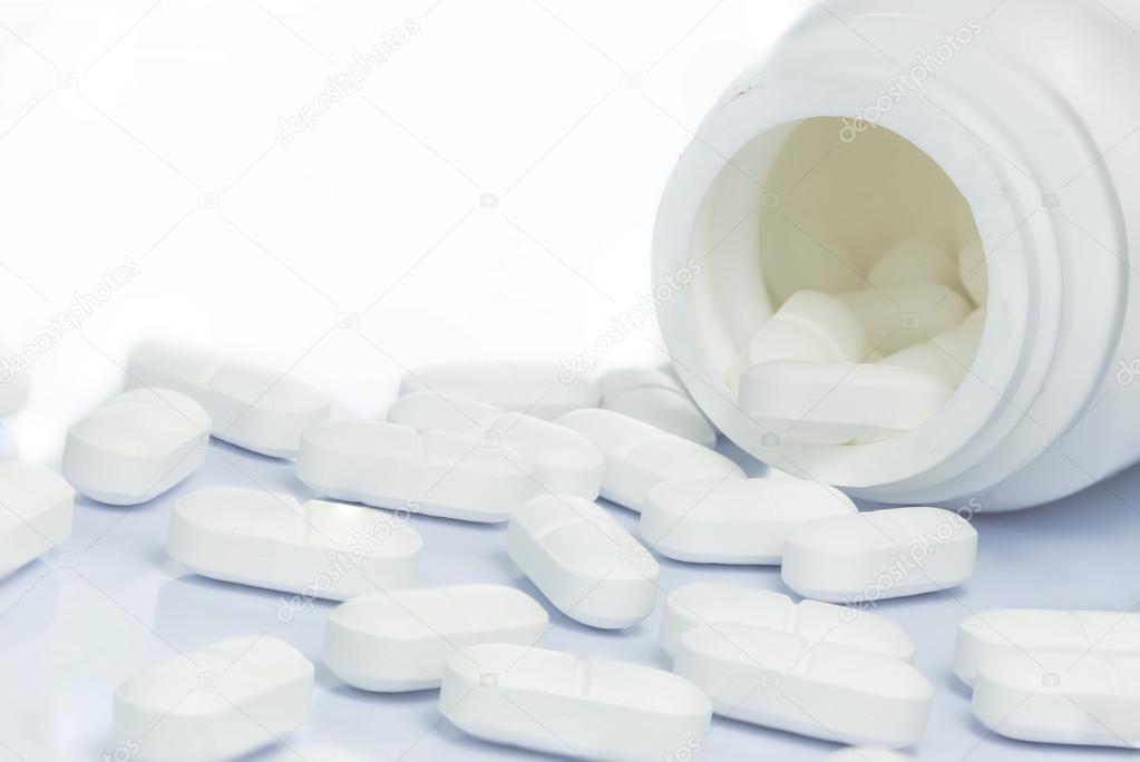 White pills spilling out of a medicine bottle