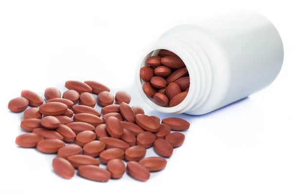 Красные таблетки, выливающиеся из бутылки с лекарством — стоковое фото