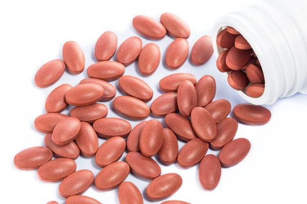 Pillole mediche rosse che fuoriescono da una bottiglia di medicinale — Foto Stock