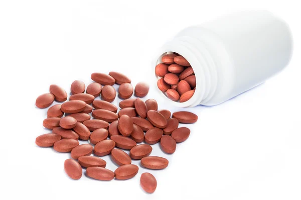Pillole rosse che fuoriescono da una bottiglia di medicinale — Foto Stock