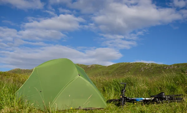 Pitched tent on meadow near mountain bike — Stock Photo, Image