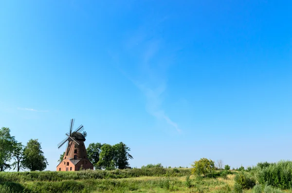 Oude bakstenen windmolen op veld op blauwe hemelachtergrond — Stockfoto