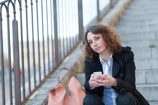 Beautiful young woman siting outside on a staircase — Stock Photo, Image