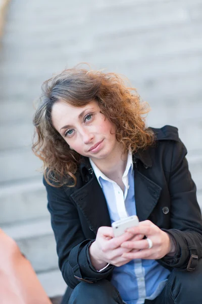 Beautiful young woman siting outside on a staircase — Stock Photo, Image