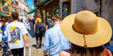 A woman with a hat walking in Venice on a sunny summer and holiday day.