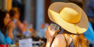Venedik 'te bir masada otururken şapkasını yudumlayan bir kadın..